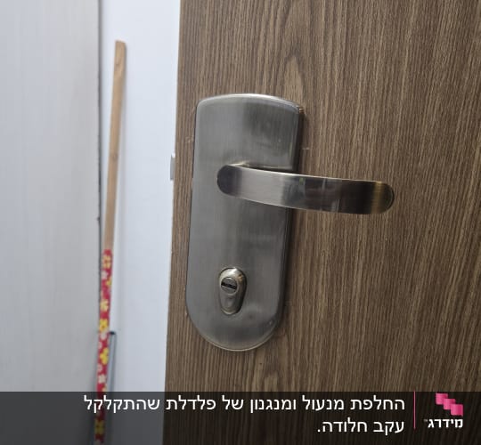 ידית דלת מתכת על דלת עץ